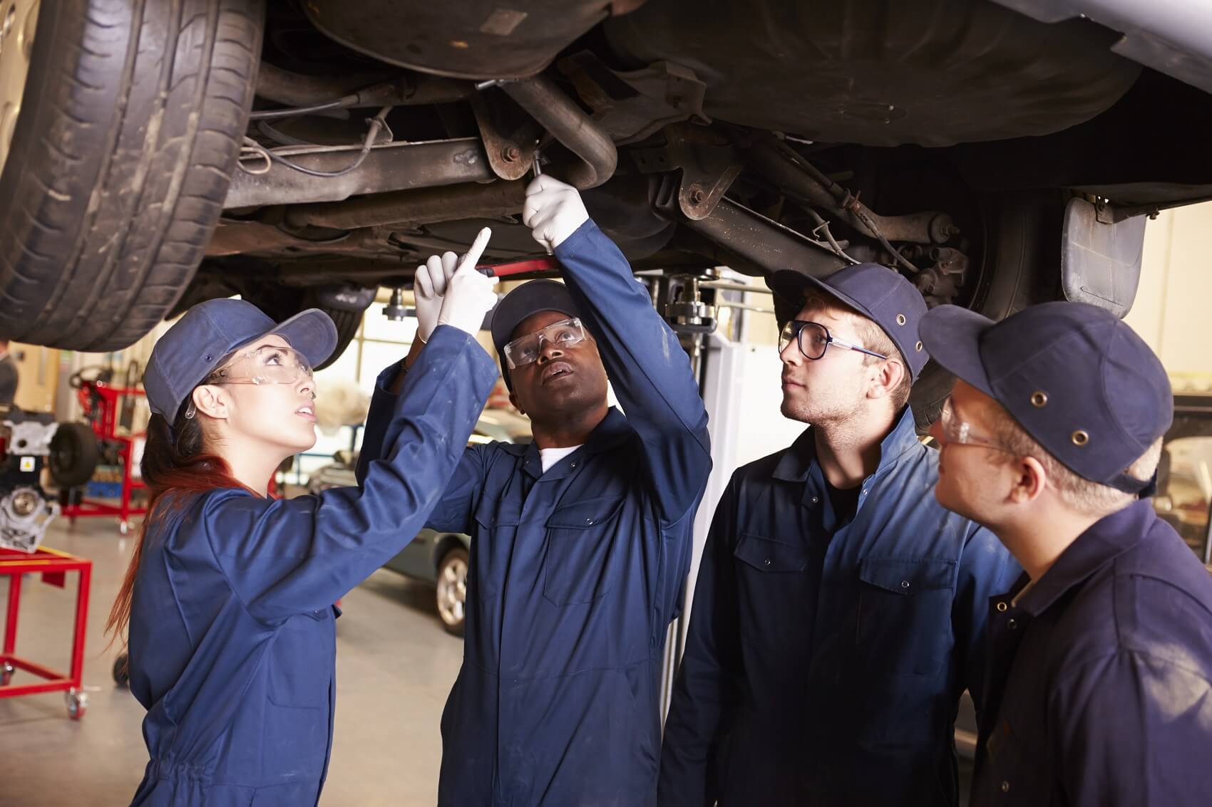 Group of automotive technicians inspecting the underside of a vehicle