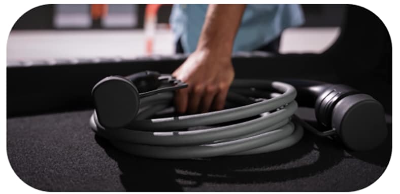 A person grabs an electric vehicle charger from their trunk.