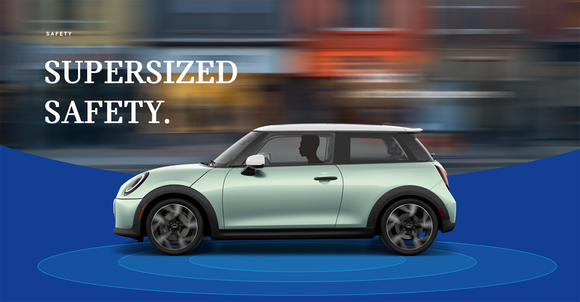 The side-view of a Mini Cooper Hardtop 2 Door with a blurred city street in the background and blue rings beneath
it.