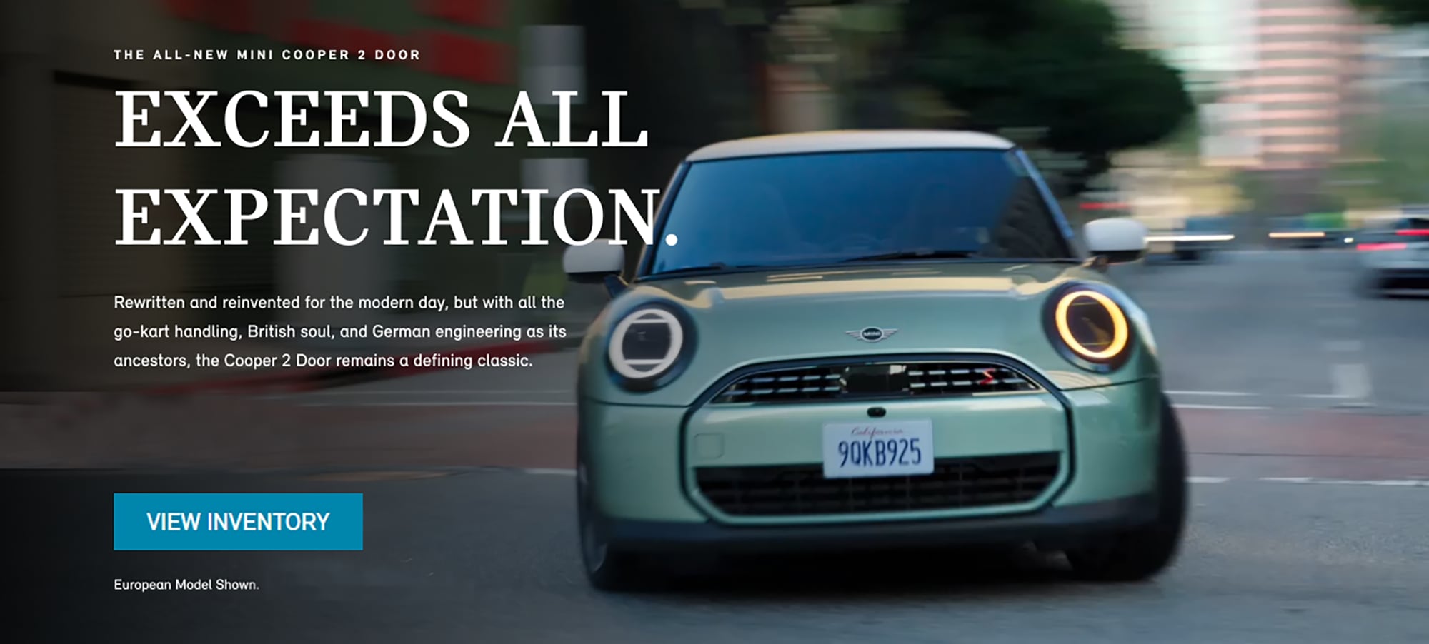 Front-to-rear view of a MINI Cooper 2 Door driving on city street.