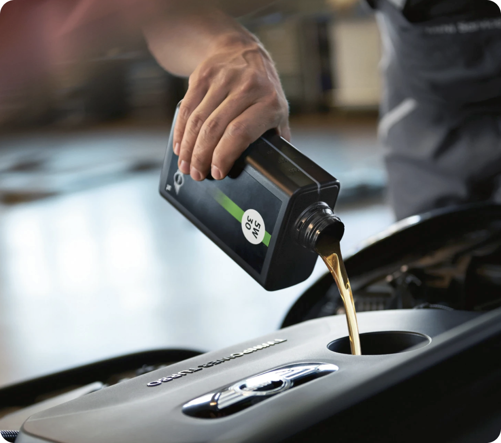 Closeup view of hand pouring motor oil into an engine with the background blurred out.