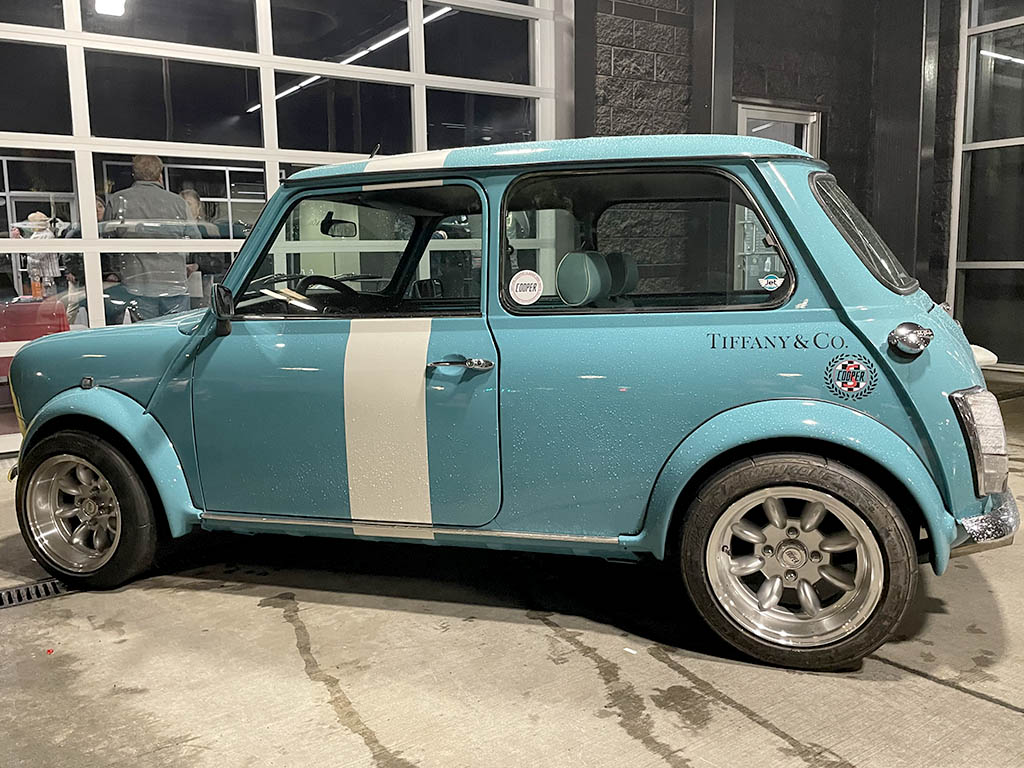 A vintage blue MINI sitting in front of the MINI of Portland building