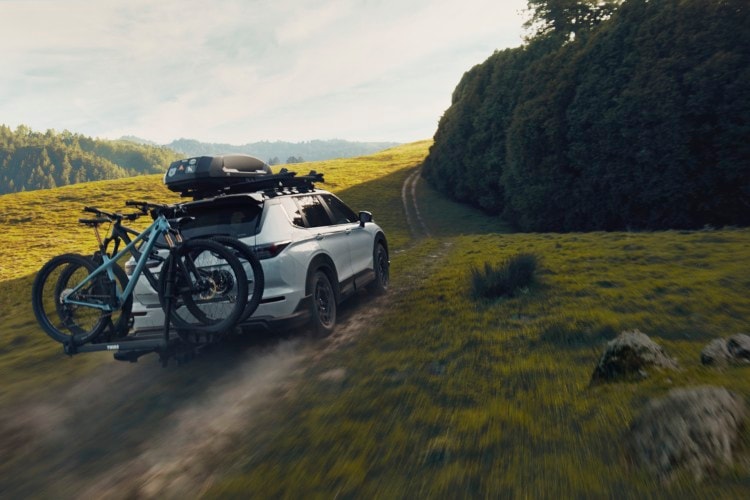 Back of White Mitsubishi Outlander Trail with bikes and roof rack