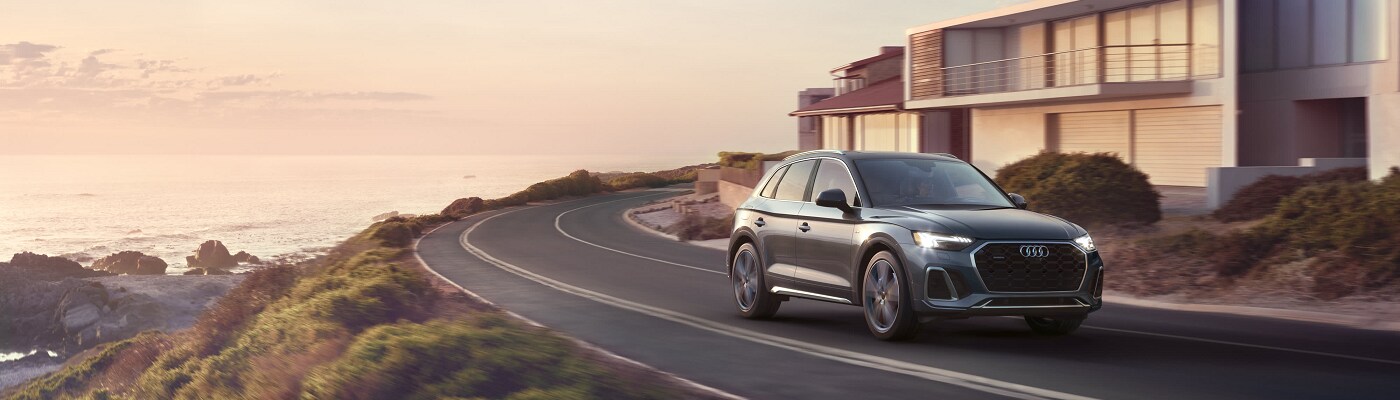 Grey Audi Q5 e driving on a road by the coast