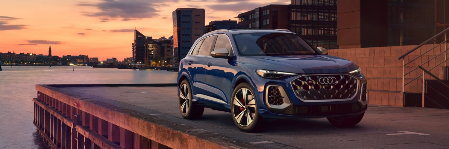Audi SQ5 parked on a waterfront city street at sunset