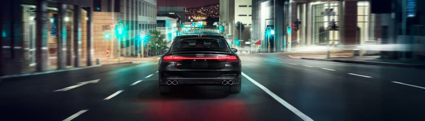 Audi S7 driving down an empty city street at night