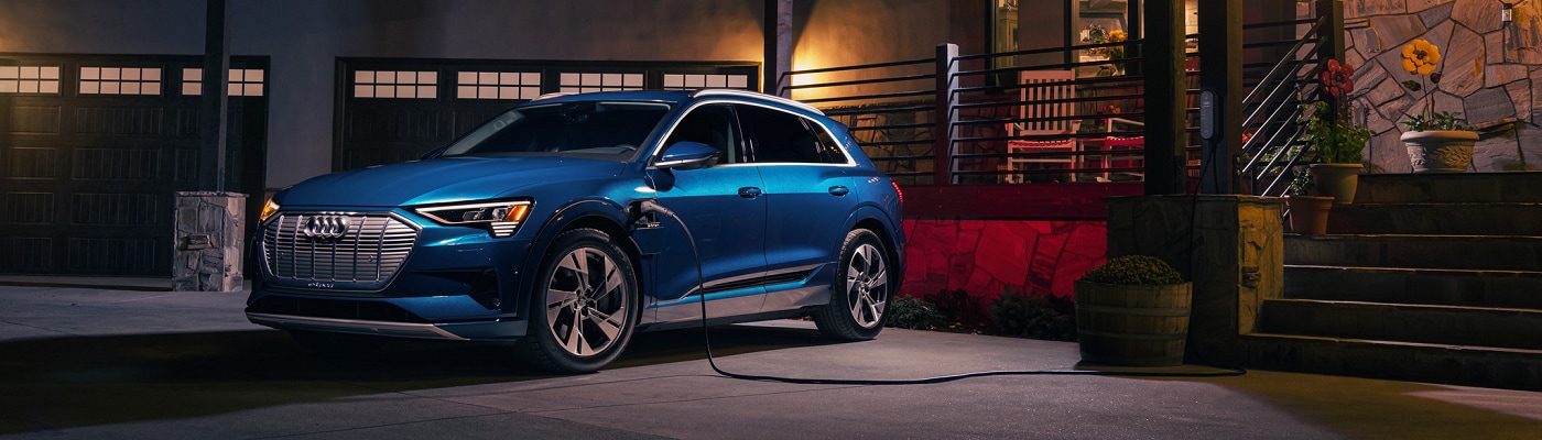 Audi e-tron charging in front of a house at night