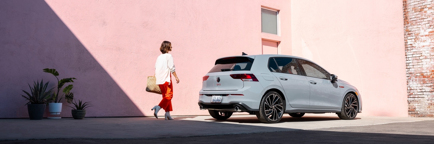 Gray VW Golf GTI parked in front of a pink building
