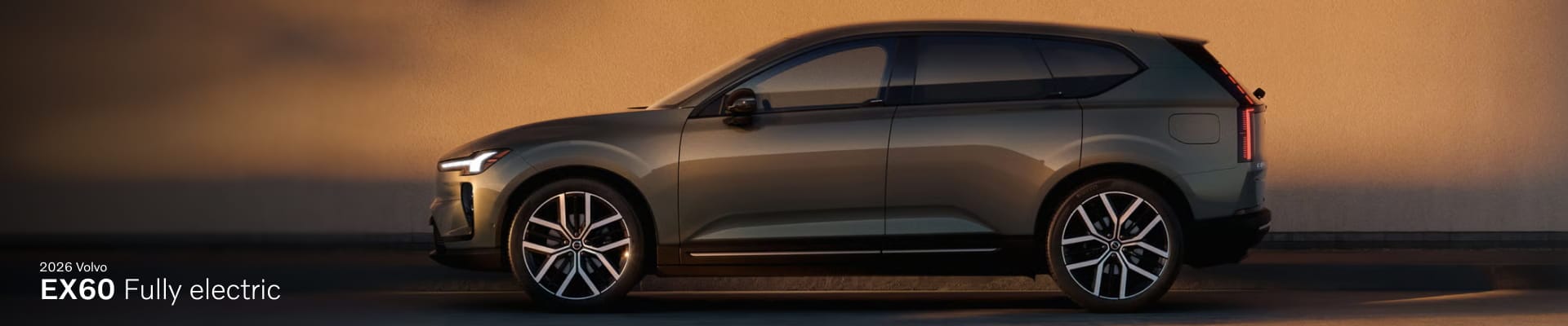 Side view of a sleek, modern 2026 Volvo EX60 electric SUV against a warm, sunset-lit backdrop.