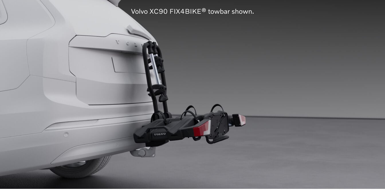 Rear-quarter studio view of a Volvo XC90 Ultra showcasing a hitch-mounted FIX4BIKE towbar bicycle rack accessory.