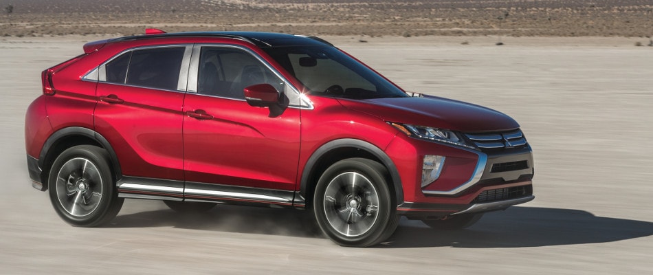 2018 Eclipse Cross Trims A red Mitsubishi Eclipse Cross driving through an open dirt road