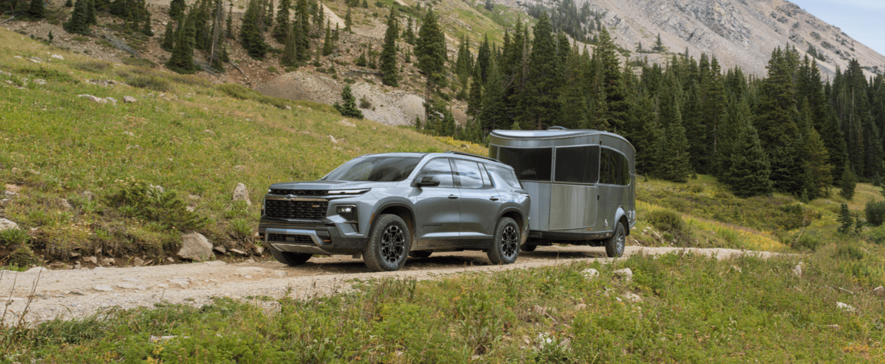 Chevrolet Traverse towing a small travel trailer along a dirt mountain