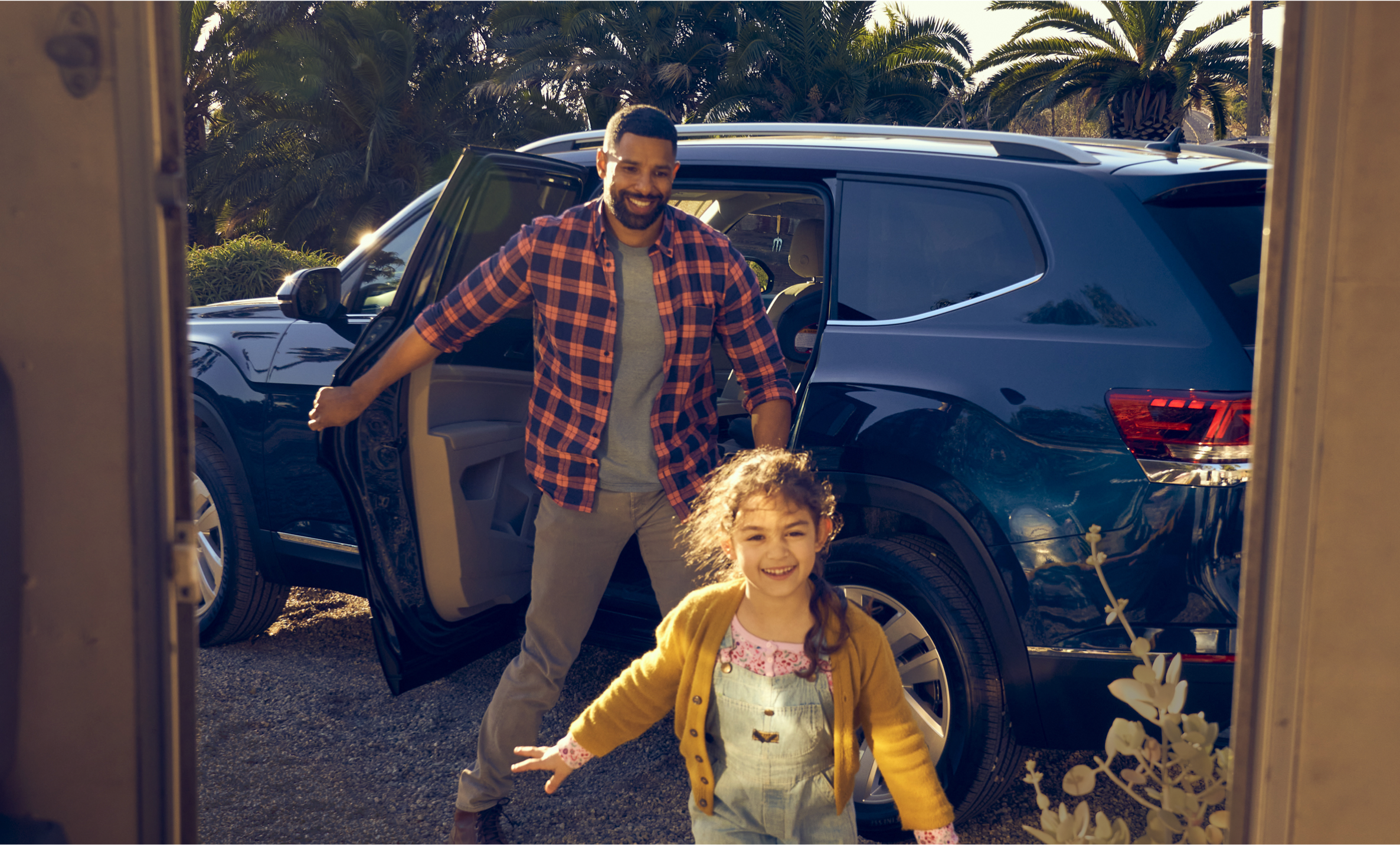Little girl getting out of Volkswagen vehicle smiling with her dad