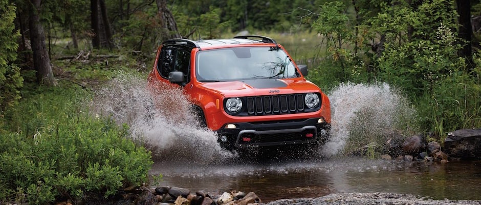 An Orange 2018 Jeep Renegade Driving through a river