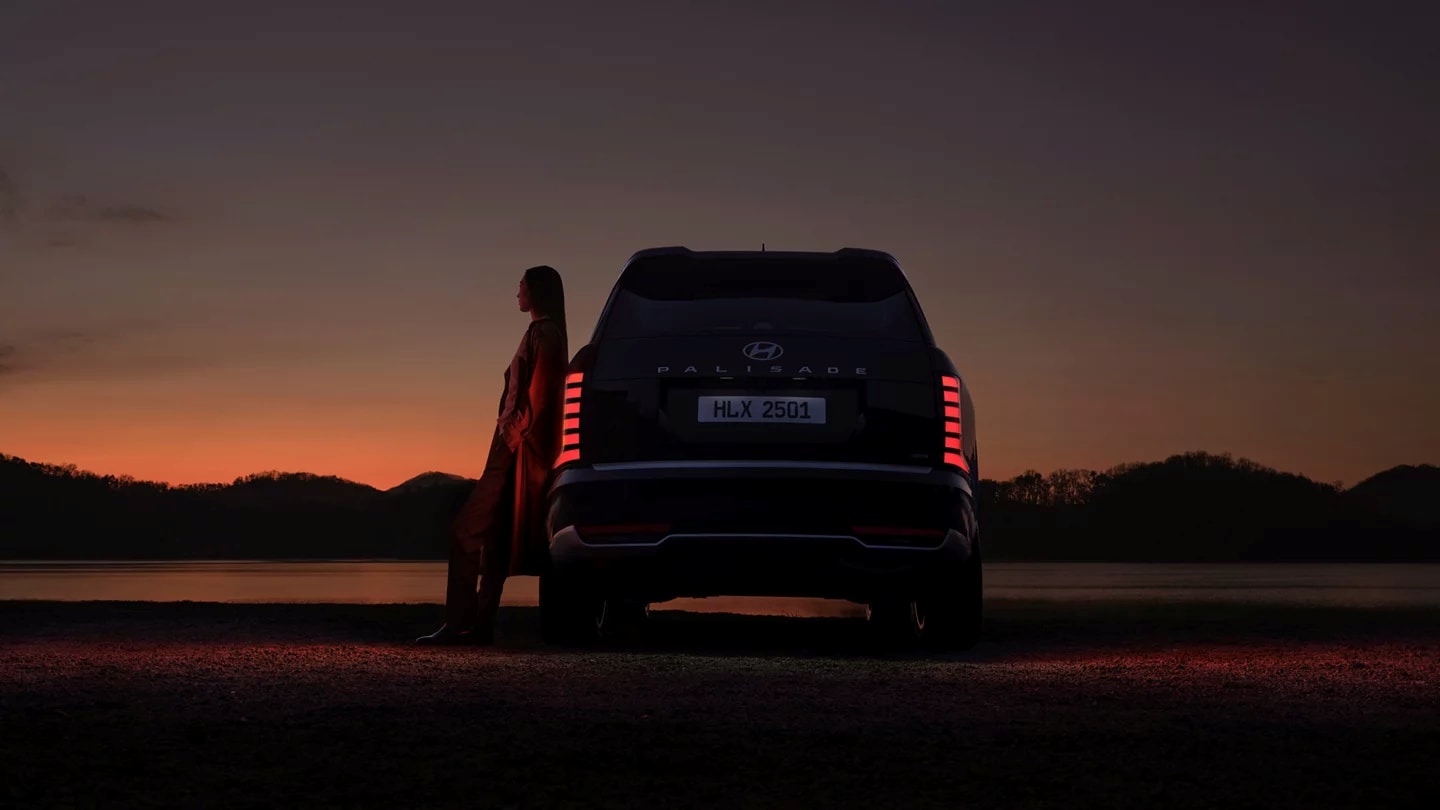 2026-hyundai-palisade-back-view-at-sunset-with-woman-leaning-on-car.png