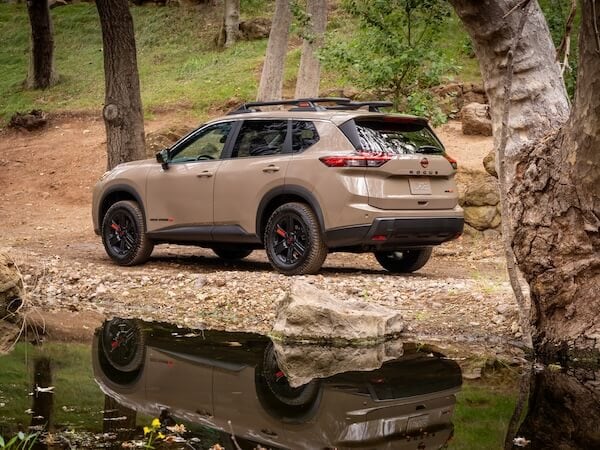 2026 Nissan Rogue Rock Creek parked on a rugged trail with adventure-inspired styling, all-terrain tires, and standard Intelligent All-Wheel Drive.