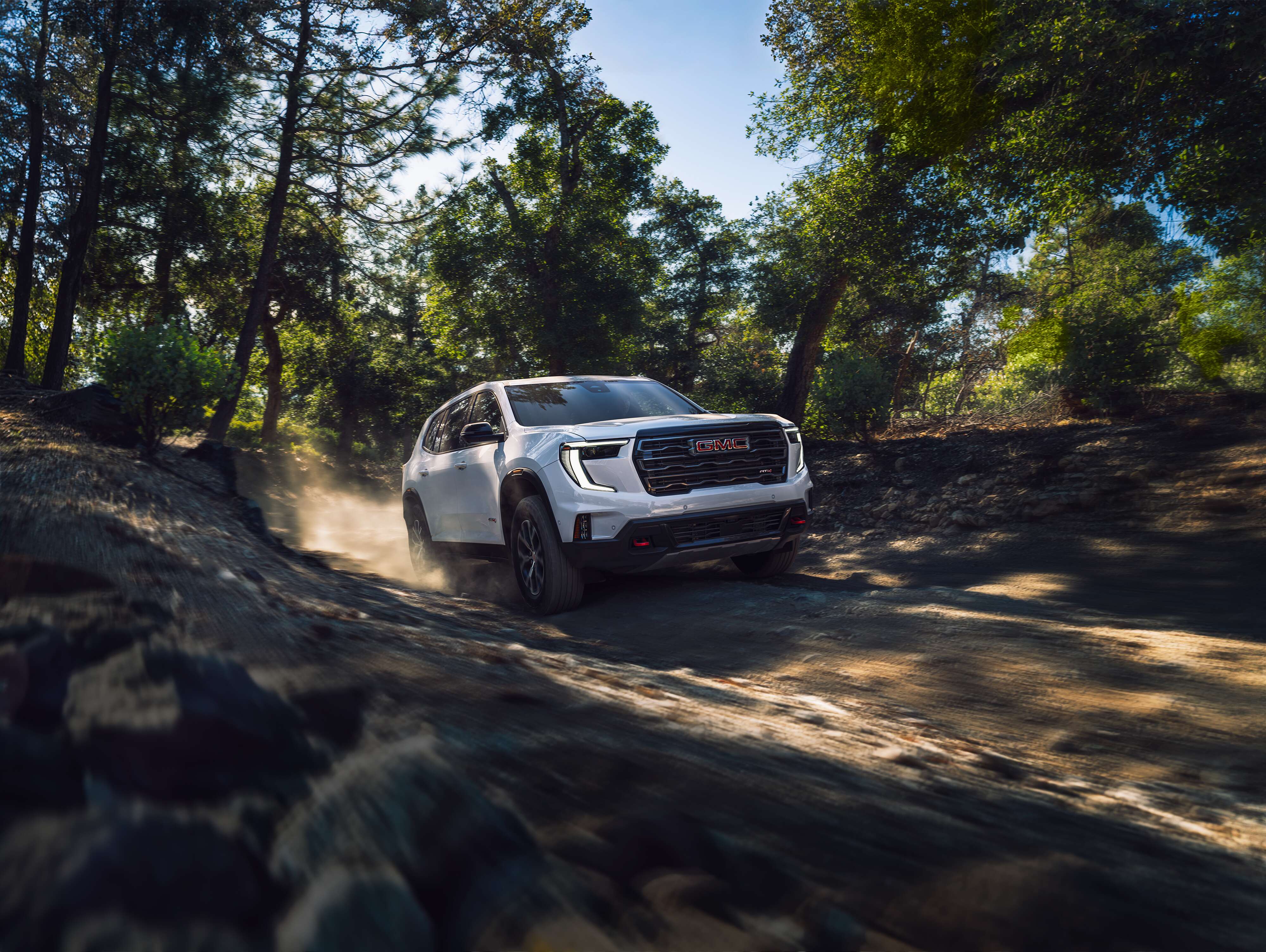 GMC Acadia AT4 GMC Acadia AT4 driving off-road on a rugged dirt trail.