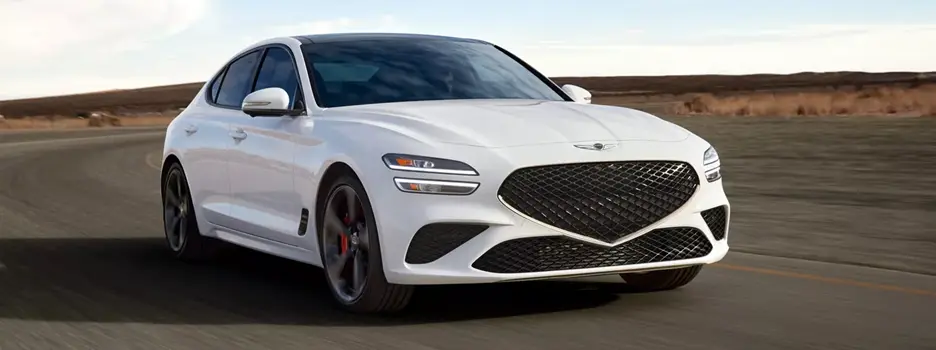 White Genesis G70 driving down street