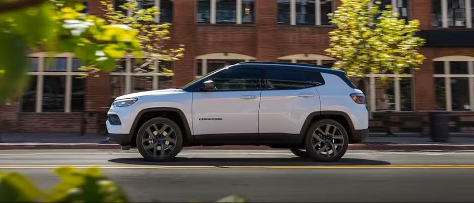 white jeep compass driving in motion down street