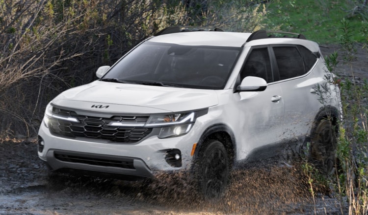 White Kia SUV driving in mud