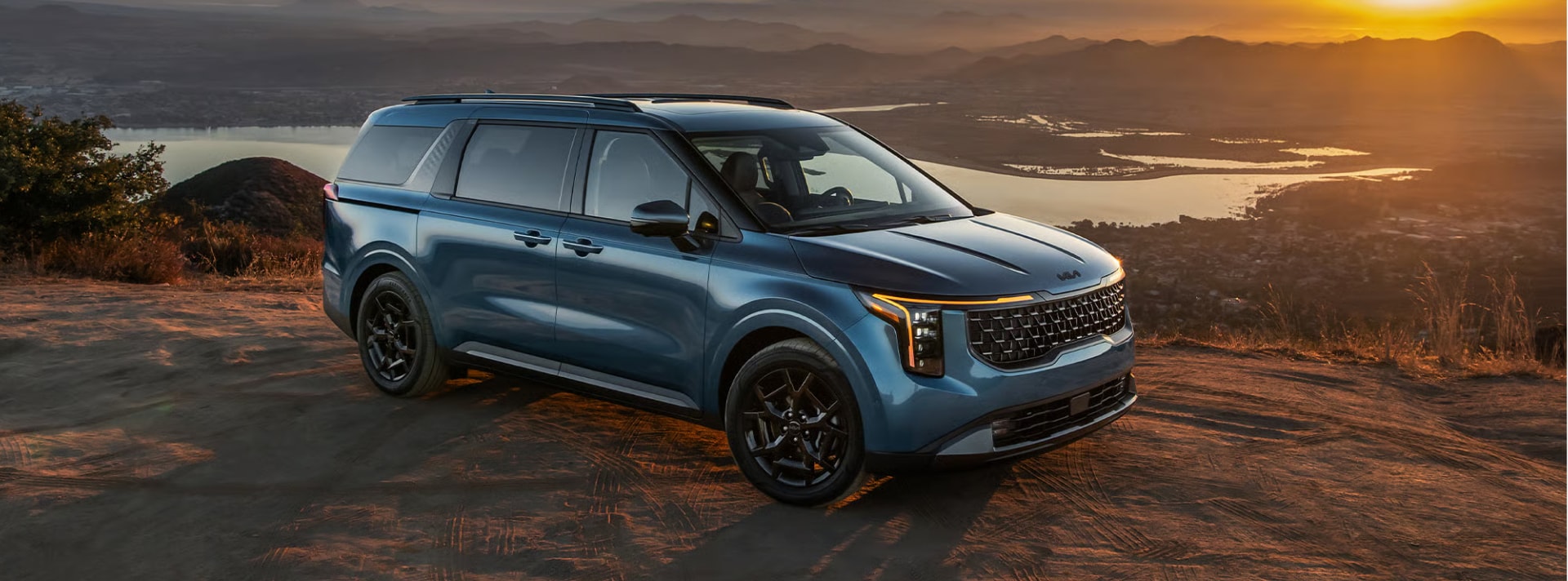 Blue Kia SUV parked in front of a cliff