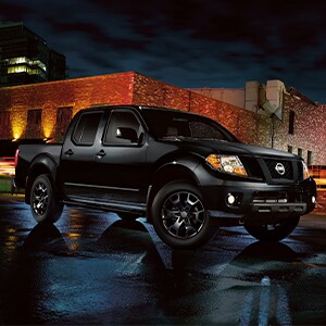 Black Nissan Frontier parked in city at night