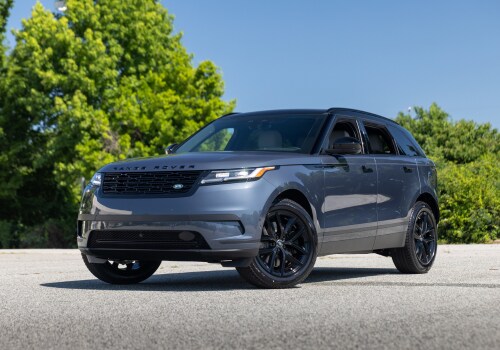 Gray 2025 Range Rover Velar SUV parked on a paved surface with trees in the background