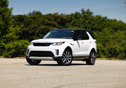 White Land Rover Discovery parked on a paved surface with trees in the background