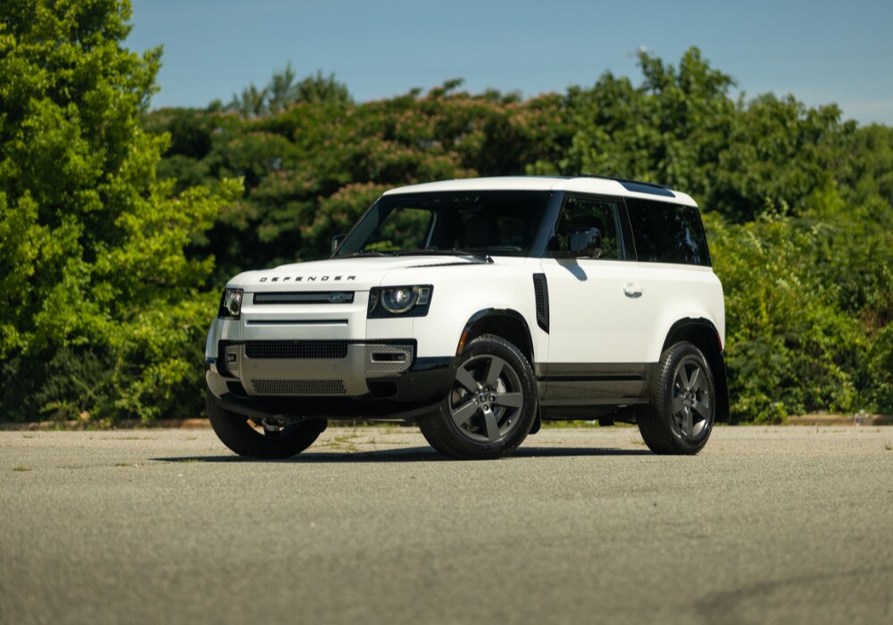 land-rover-defender-90-for-sale.png 2025 Land Rover Defender 90 parked in paved lot in front of a tree line