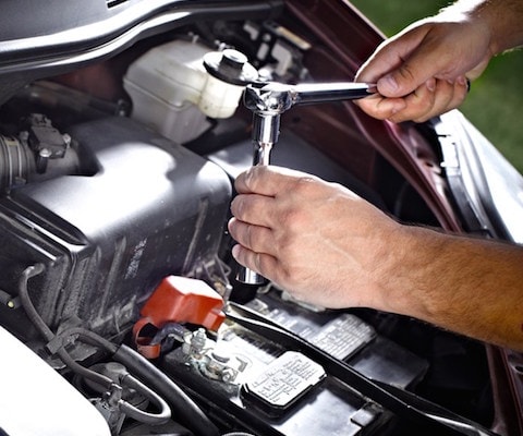 A technician using a tool to fix a battery in a car