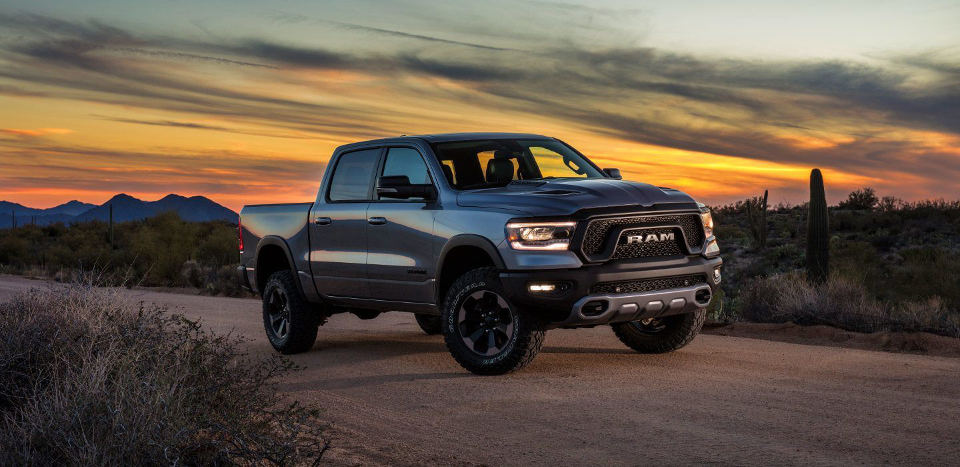 A 2019 Ram 1500 driving down a road during a sunset