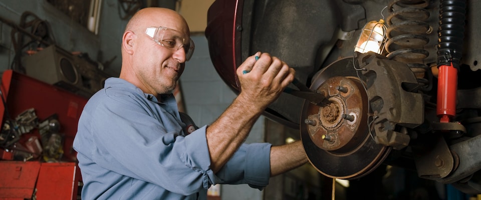 A maan using pliers to work on fixing brakes