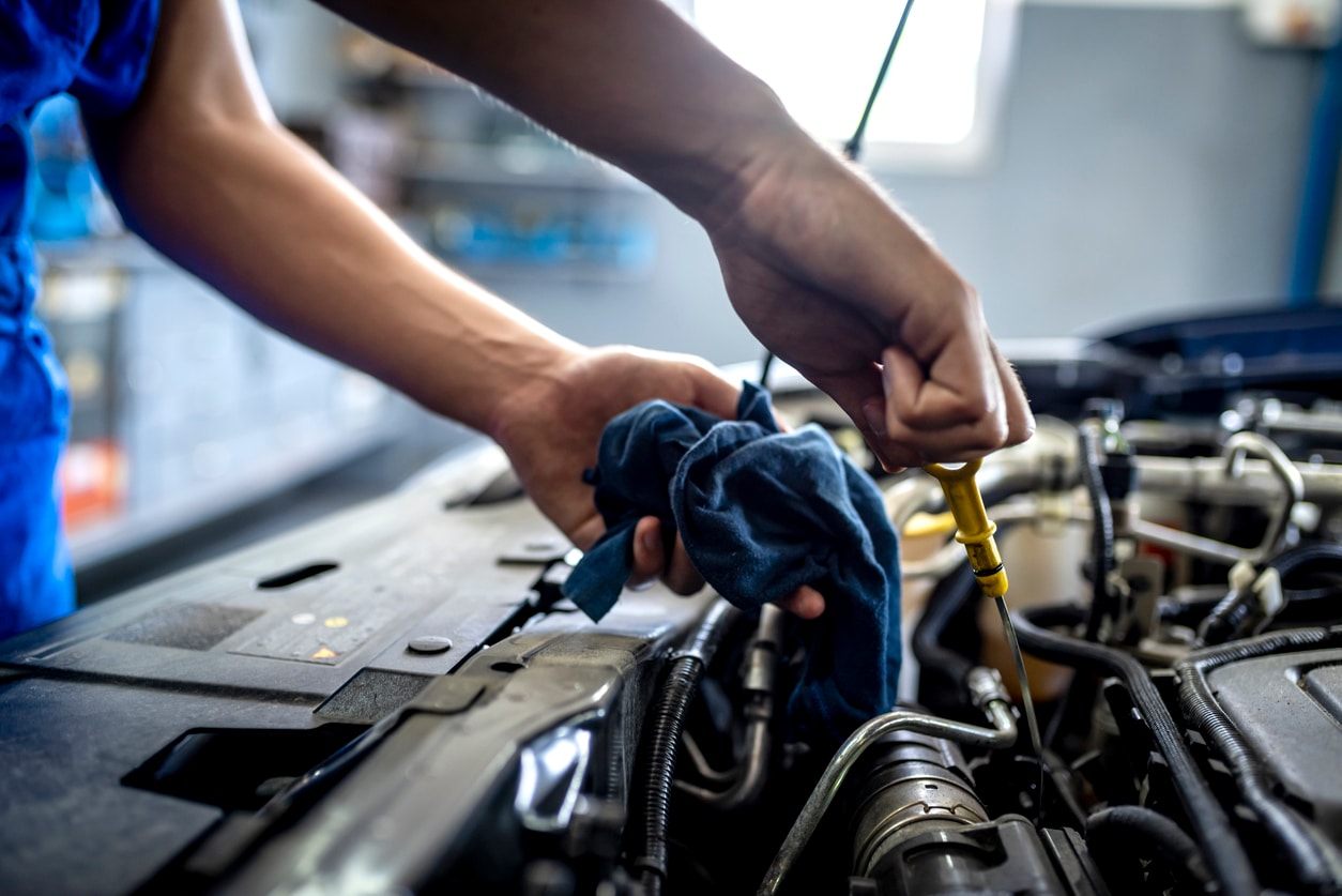 male mechanic measuring the oil level of an engine at an auto shop. Mechanic checking the oil level in a car service garage.