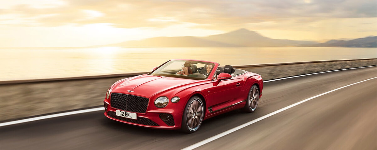 Red Bentley Continental GT driving down the coast
