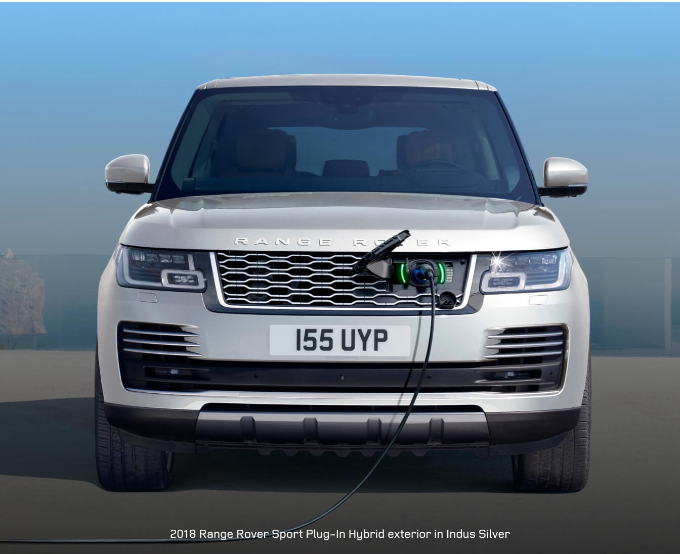 2018 Range Rover PHEV charges from a wall port at a modern oceanfront villa.