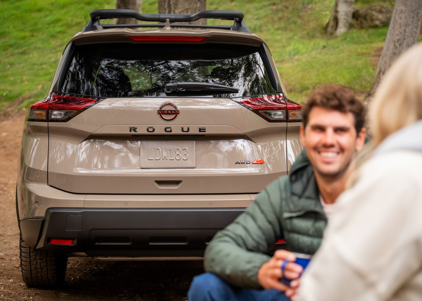 Nissan Rouge on campground with man sitting near it