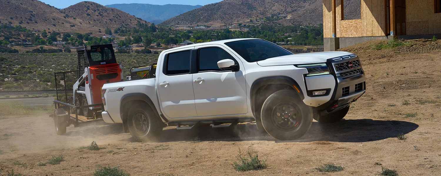 The new 2026 Nissan Frontier hauling a trailer with equipment on it