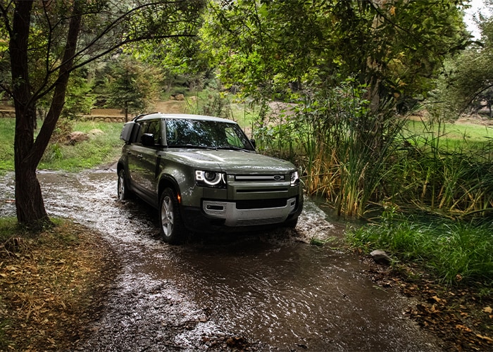 Defender driving through a forest stream