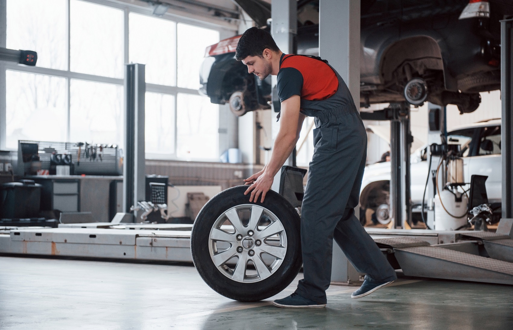 Certified Cadillac Technician rolling a tire while working on a vehicle