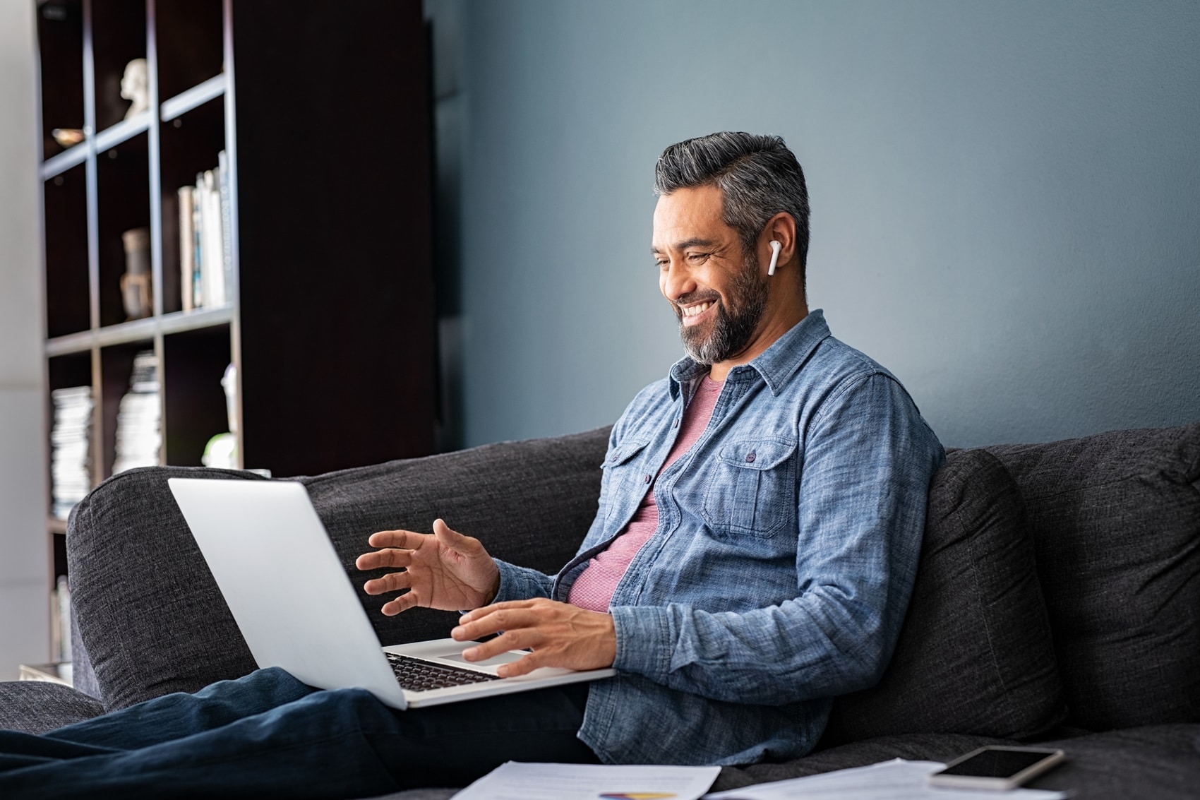 Man smiling while sitting on the couch reviewing financing for his Cadillac
