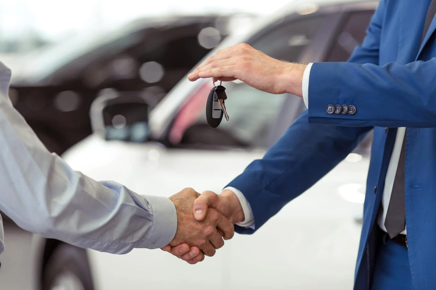 GMC Sales Team member handing keys to used vehicle to customer while shaking hands