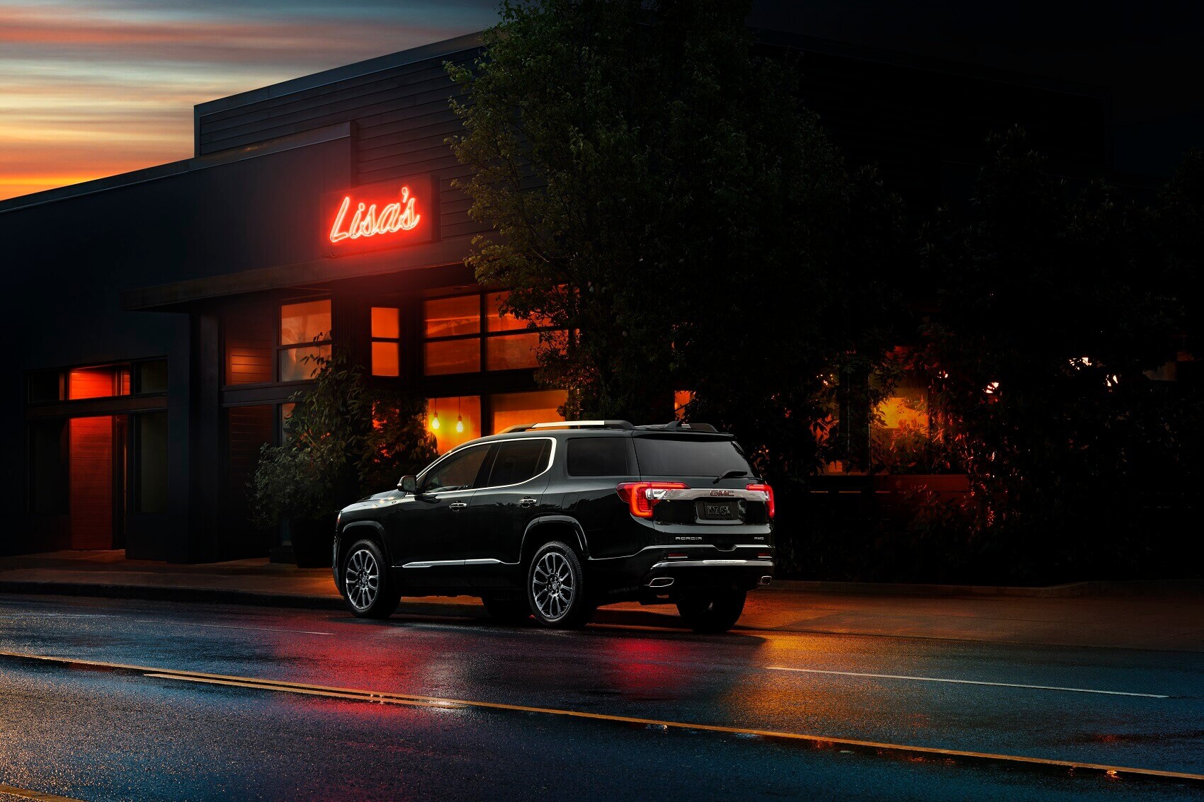 Used GMC Acadia parked on the street outside restaurant in the evening