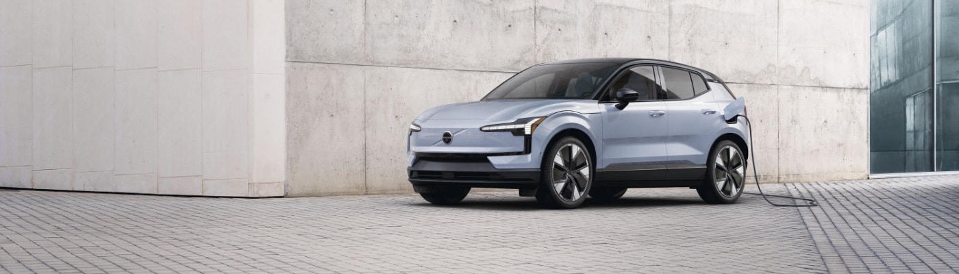 New Volvo EX30 charging next to a light colored stone wall