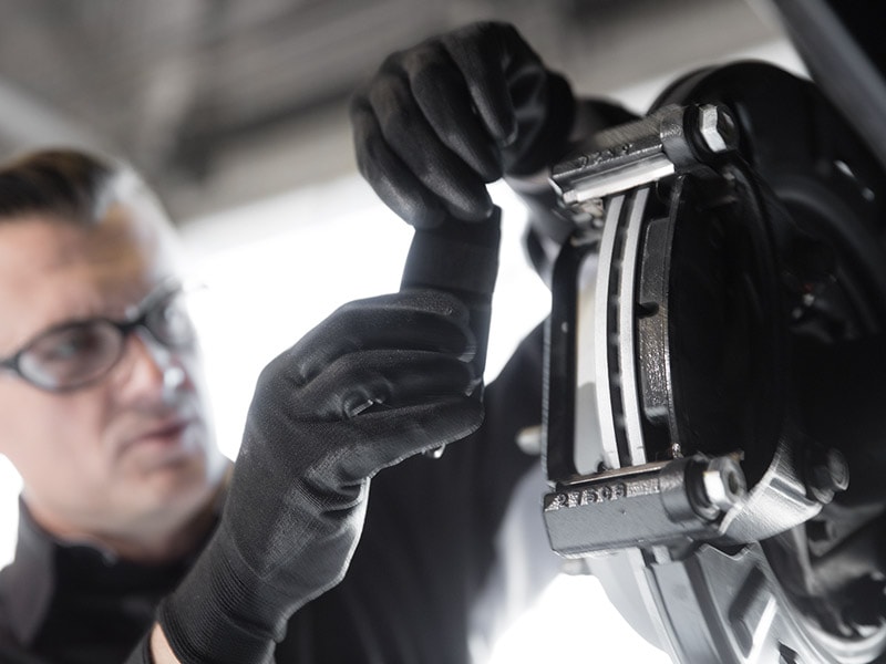 Technician inspecting brake pads and caliper hardware during a Cadillac brake service at Ocean Cadillac