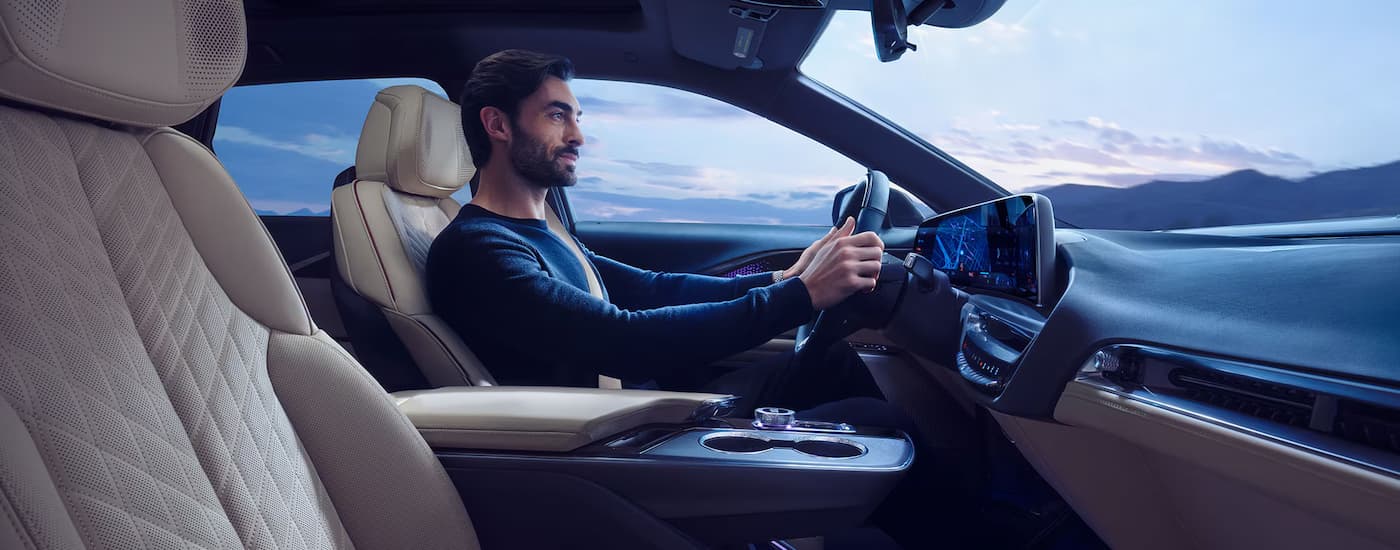 Man driving in a 2025 Cadillac LYRIQ on a cloudy day.