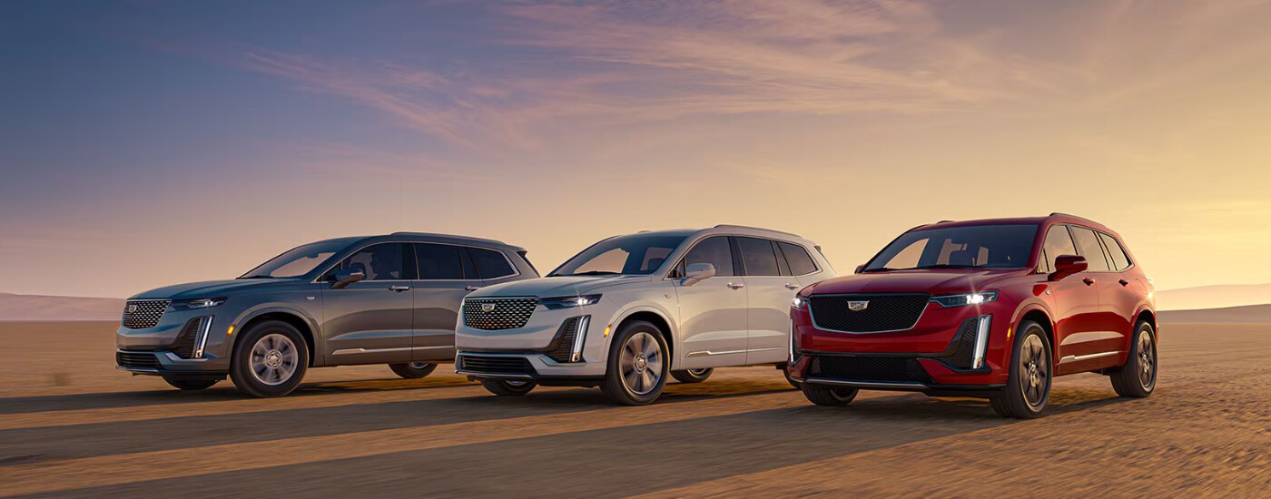 A silver, a red, and a white 2026 Cadillac XT6 parked side by side off-road