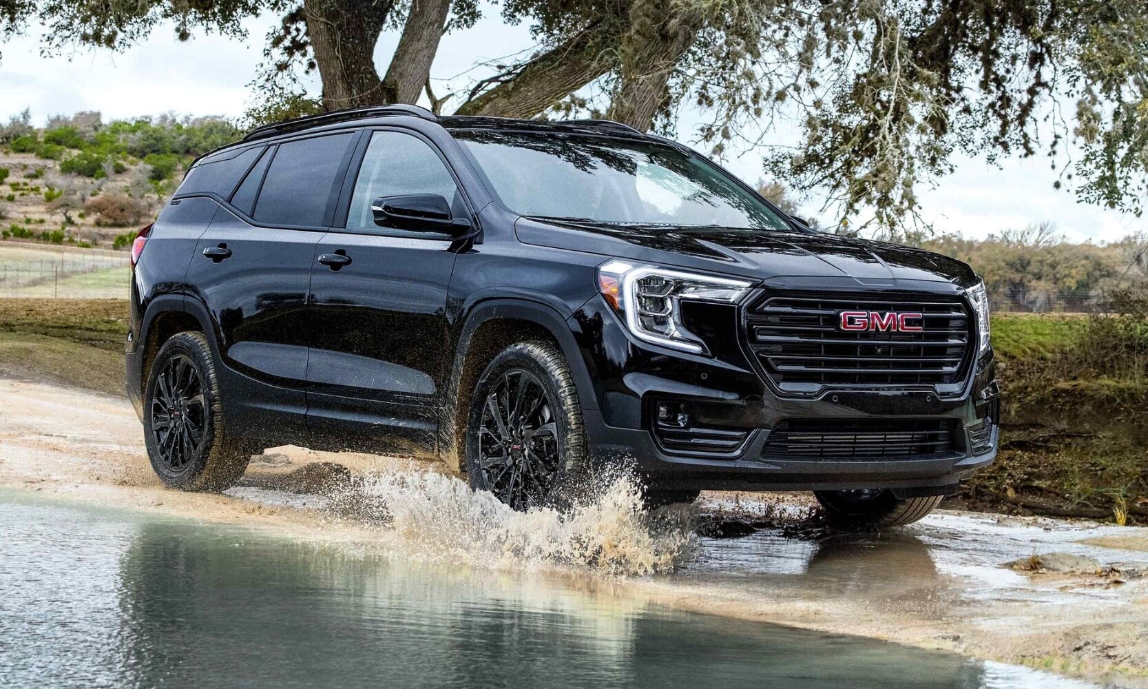 2023 GMC Terrain equipped with the Elevation Edition Package in black exterior color driving through a puddle making a splash