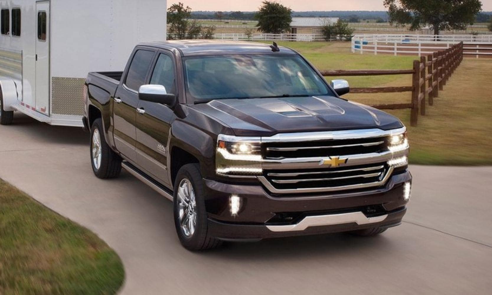 Used 2017 Chevy Silverado 1500 High Country in dark red color towing a horse trailer