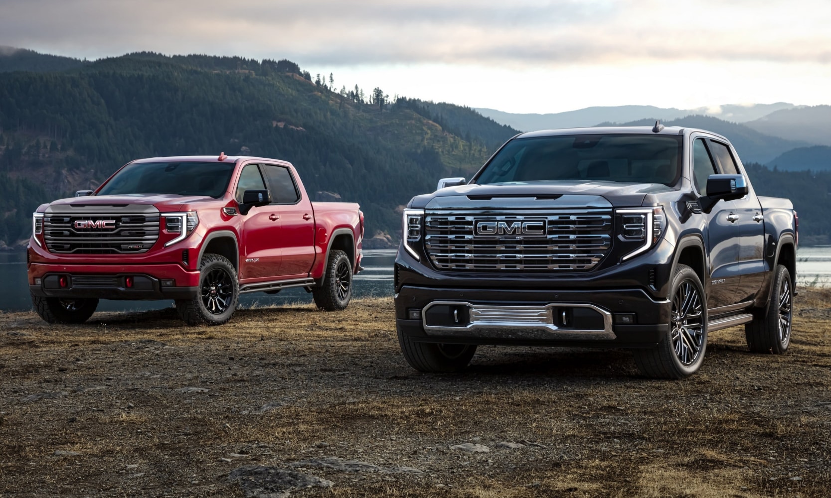 New 2022 GMC Sierra 1500 Light Duty Truck Price & Trim Levels - Octane Buick GMC of Santa Fe.png New 2022 GMC Sierra 1500 AT4 and Denali trim levels parked side by side on a riverbank near mountains