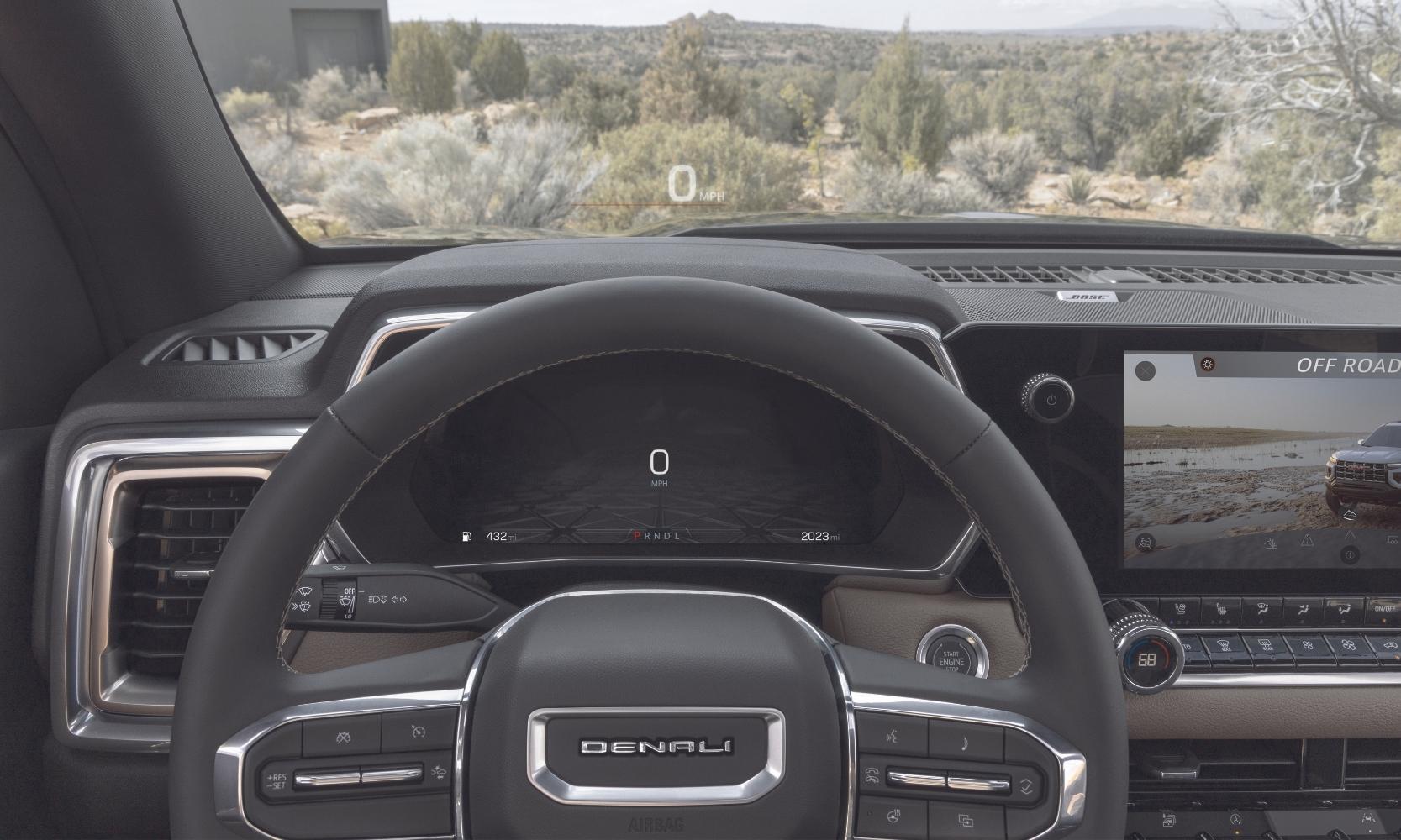 Close up of the dashboard in the 2023 GMC Canyon truck showing the head up display and instrument panel behind the steering wheel